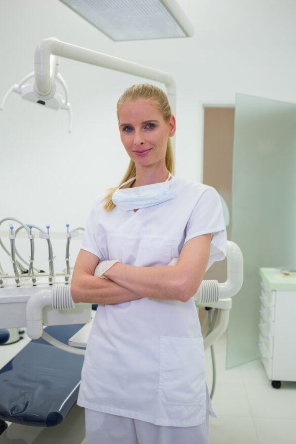Portrait Of Smiling Dentist Standing With Arms Crossed At Clinic